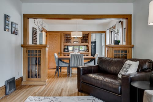 A cozy living space leading to a stylish dining area, featuring modern decor and warm wooden elements.
