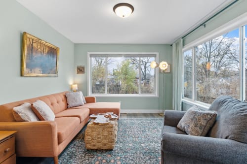 A cozy and stylish living room with an orange sectional couch and natural light.