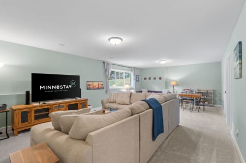 A cozy living room featuring a media console, soft furnishings, and a dining area.