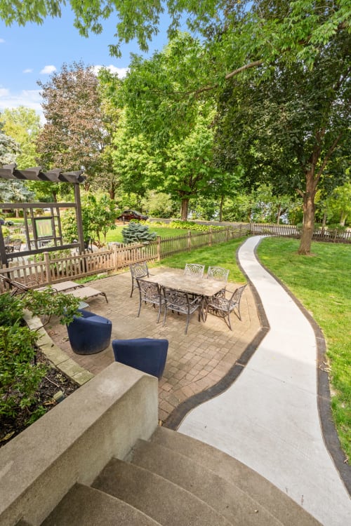A serene garden featuring a patio with a dining table surrounded by greenery.
