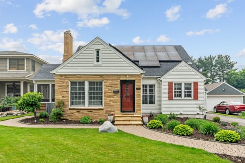 Charming suburban home with modern solar panels and lush landscaping.