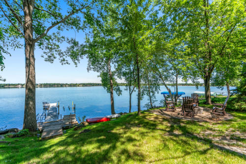 A tranquil lakeside view featuring a wooden dock and cozy seating area.
