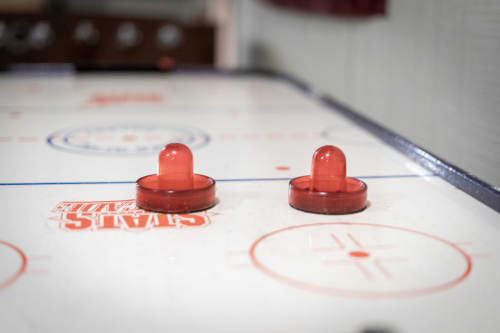 Close-up of a classic air hockey table with red pucks in play.