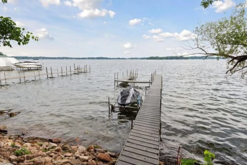 A peaceful lakeside scene with a wooden dock and a covered boat.