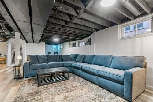 Cozy basement living area with a large blue sectional sofa and industrial accents.