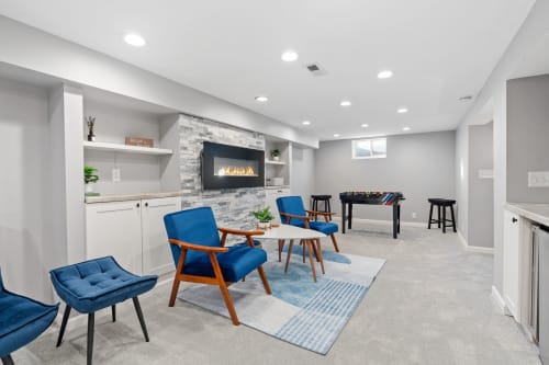 A contemporary basement lounge featuring cozy seating, a modern fireplace, and a foosball table.