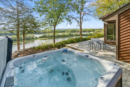 A serene outdoor hot tub overlooking a picturesque river landscape.