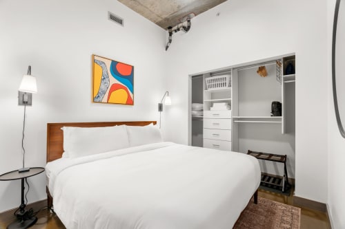 A cozy modern bedroom with a large bed and colorful abstract art.