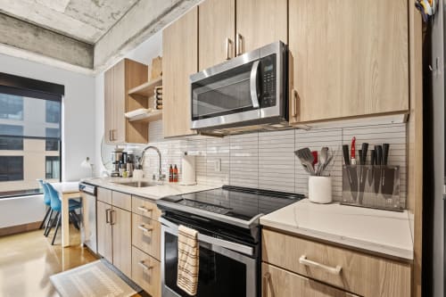 A modern kitchen with light wood cabinets and stainless steel appliances.