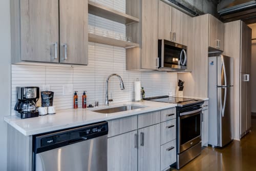 A stylish modern kitchen with light wood cabinets and stainless steel appliances.