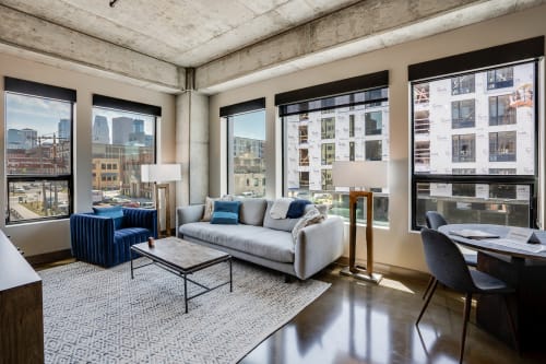 A stylish and modern apartment living area with exposed concrete elements and a view of the city skyline.