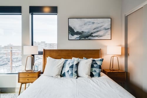 A stylish modern bedroom with geometric pillows and a city view.
