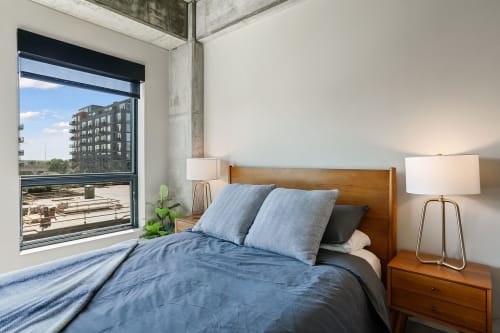 A contemporary bedroom with a large window and urban view.