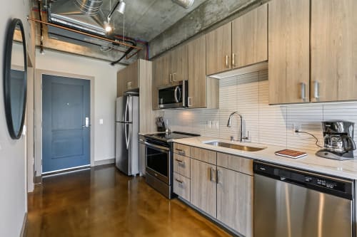 Modern industrial kitchen with sleek appliances and light cabinetry.