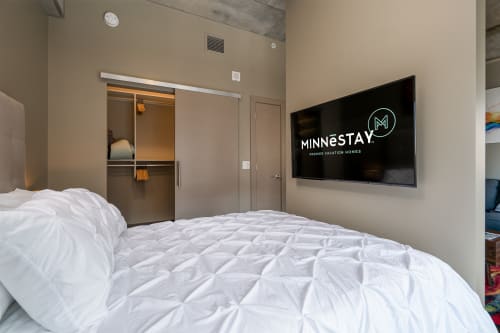 Modern bedroom with a minimalist design featuring a cozy bed and a TV.