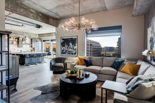 A modern living area featuring a stylish sectional sofa, open kitchen, and city views.