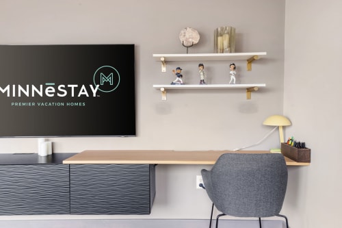 A stylish modern workspace featuring a sleek desk, decorative shelf, and MINNESTAY branding.