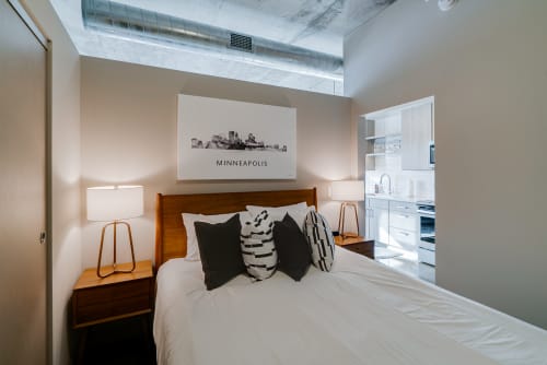 A stylish bedroom featuring a contemporary design with a Minneapolis skyline art piece.