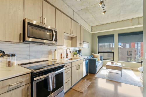 A stylish, modern kitchen and living area in an apartment showcasing natural light and contemporary decor.