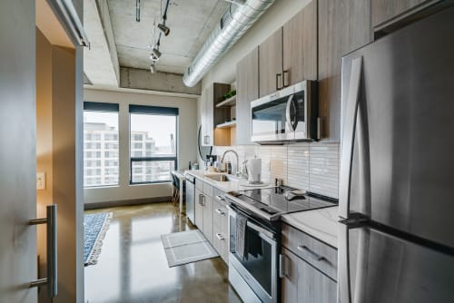 A stylish and modern urban kitchen with concrete flooring and city views.