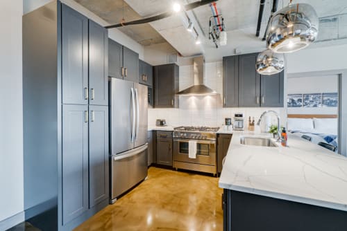 A modern kitchen with dark cabinetry and stainless steel appliances.
