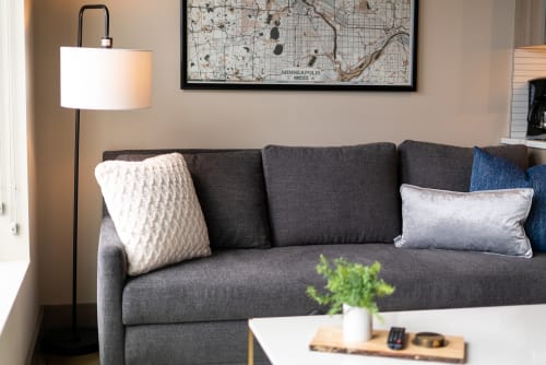 A cozy corner featuring a modern gray sofa with decorative pillows and a stylish floor lamp.