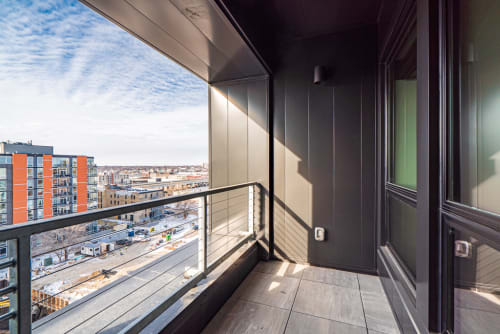 A modern balcony with a striking cityscape view, showcasing elegant design and bright sunlight.