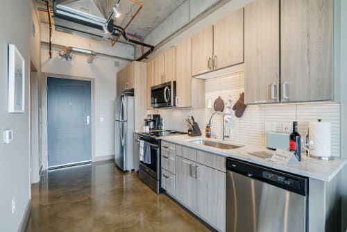 A modern kitchen featuring sleek wood cabinetry and stainless steel appliances.