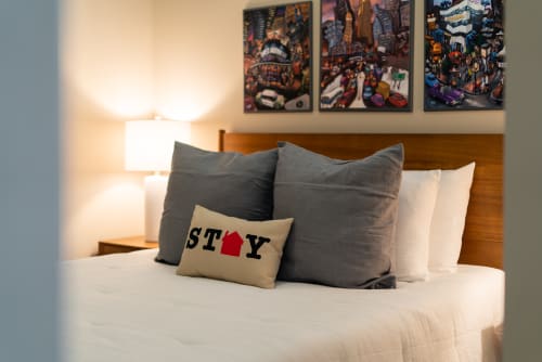 A cozy bedroom with inviting pillows and urban artwork.