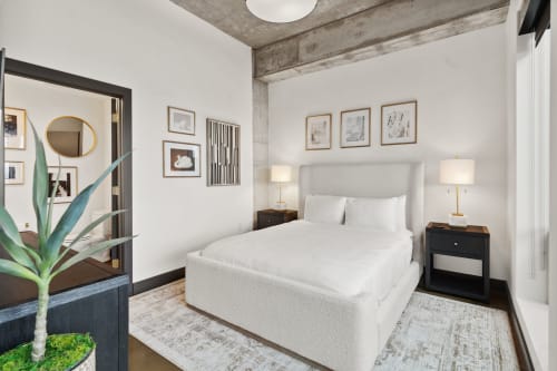 A modern bedroom with a plush bed and artistic decor.