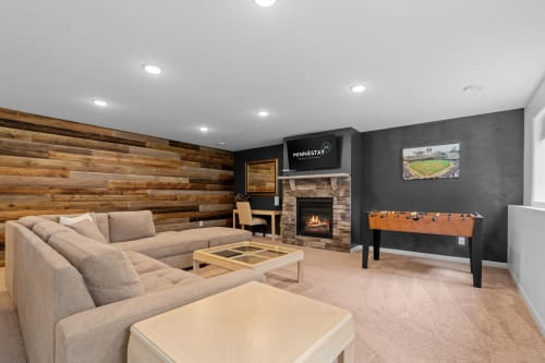 A stylish and inviting living room with a sectional sofa, fireplace, and foosball table.