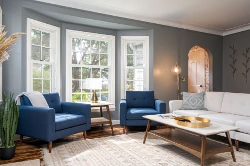 Modern living room with blue armchairs and cozy decor elements.