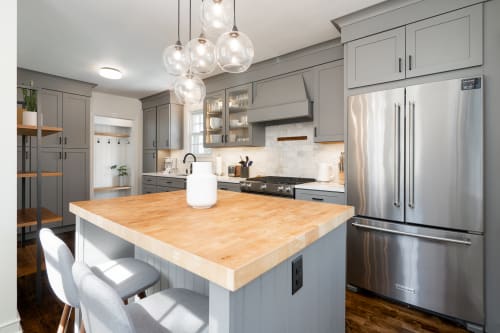 A modern kitchen with gray cabinetry and a wood-topped island.