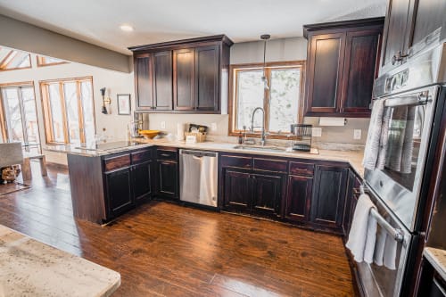 A contemporary kitchen filled with warmth and sunlight features dark wood cabinetry and elegant granite countertops.