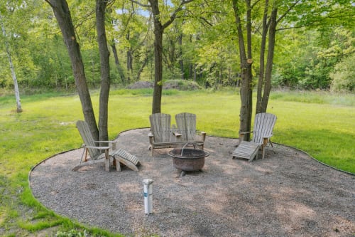 A peaceful outdoor gathering space with adirondack chairs and a fire pit.