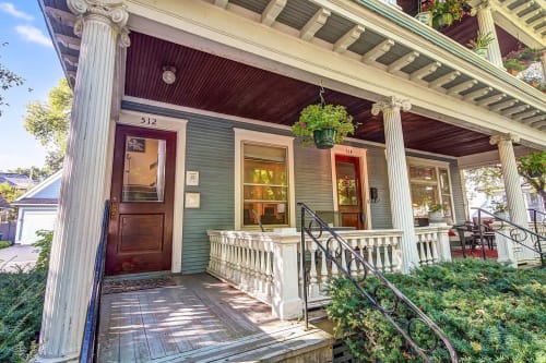 Charming entrance of a historic duplex with vibrant plants and welcoming design.