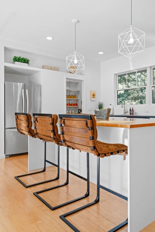 A modern kitchen featuring stylish bar stools and unique pendant lights.