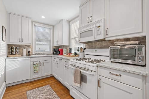 Modern kitchen with sleek white cabinetry and warm wood flooring.