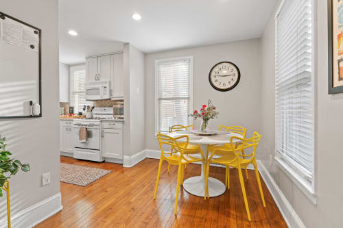 A modern kitchen area with yellow chairs and a floral centerpiece.
