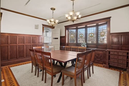 Gather around this elegant dining table surrounded by rich wood paneling and beautiful stained glass windows for memorable meals with your group.