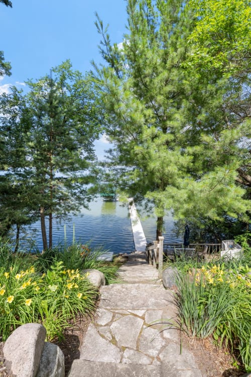 A picturesque path leading to a tranquil lakeside dock surrounded by greenery.
