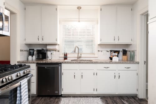 Modern kitchen with white cabinetry and granite countertops.