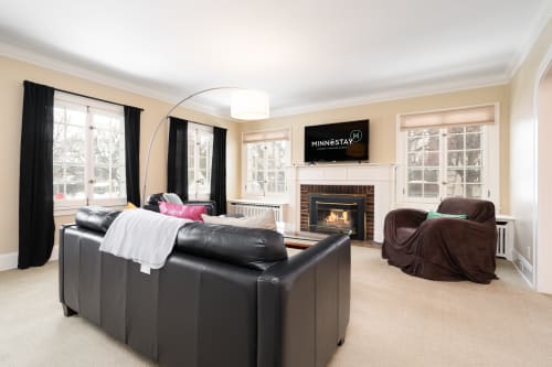 A modern and cozy living room with a black leather sofa and fireplace.