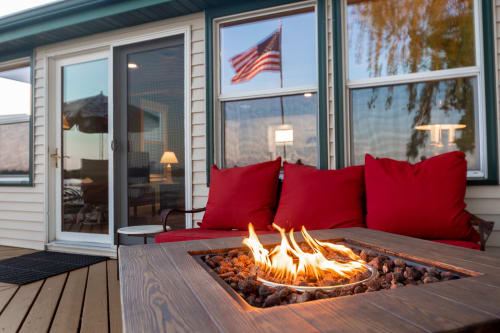 A cozy outdoor deck featuring a warm fire pit and inviting red cushions, with an American flag in the background.