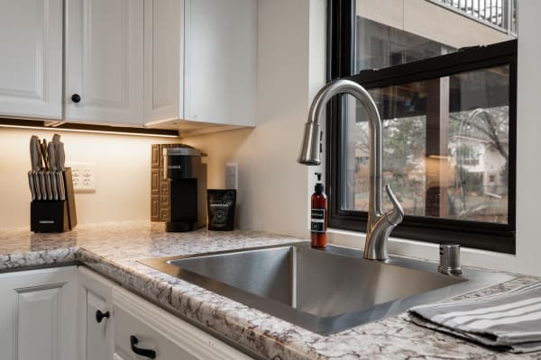 A modern kitchen with a stainless steel sink, coffee machine, and knife block.