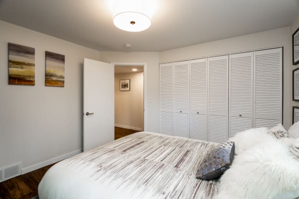 Cozy bedroom featuring a neatly made bed, abstract art, and a spacious closet.