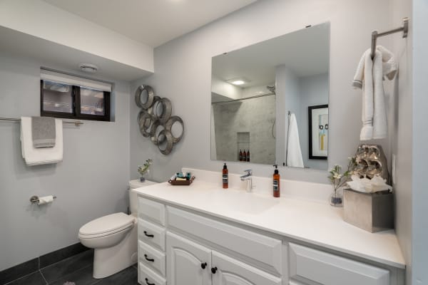 Contemporary bathroom with white vanity, circular mirrors, and neatly arranged toiletries.