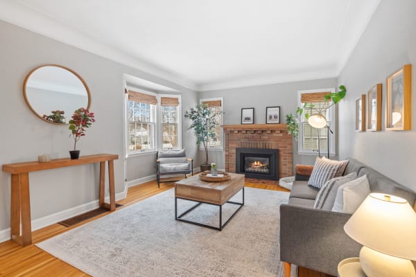 A cozy living room featuring a gray sofa, wooden coffee table, and a brick fireplace.