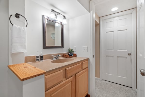 A modern bathroom featuring a vanity with mirror, towel, and decor items.