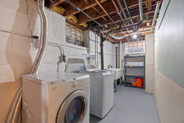 Basement laundry room with a washing machine, dryer, and utility sink.